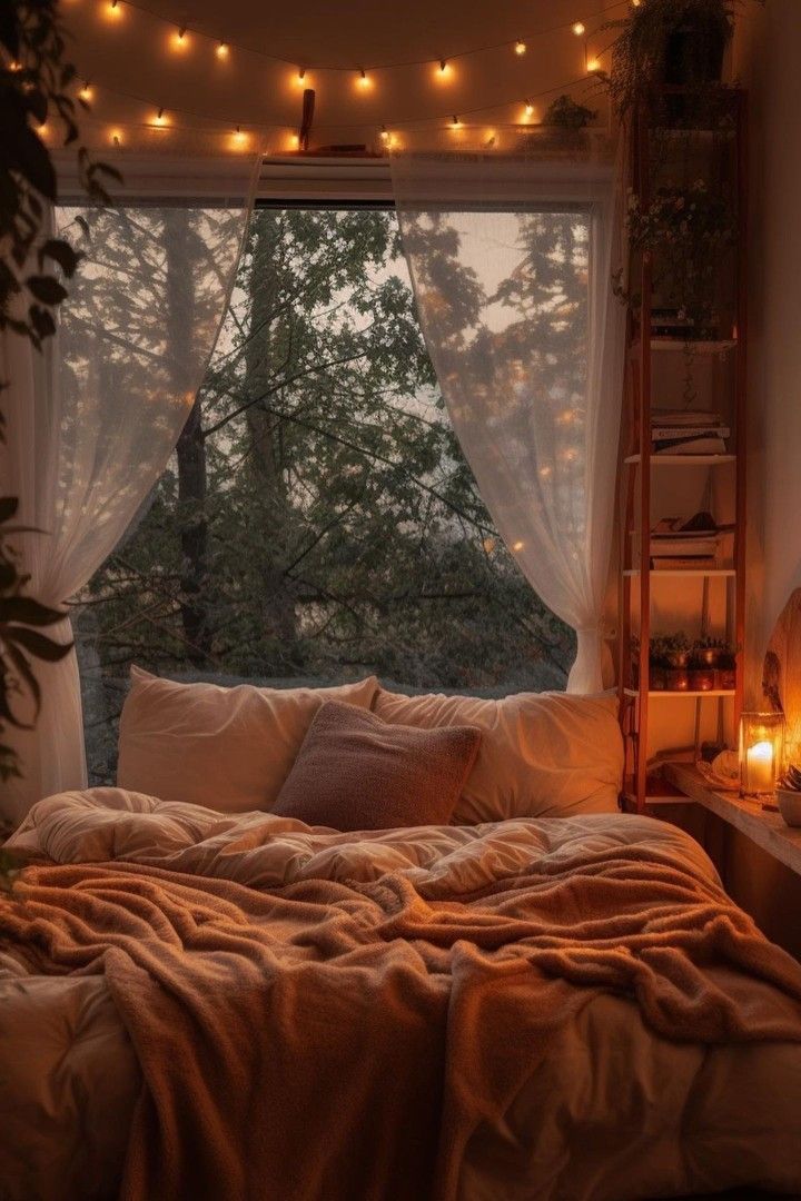 an unmade bed in front of a window with fairy lights