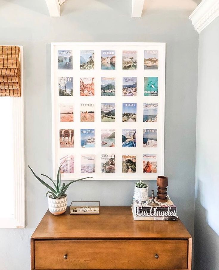 a wooden dresser topped with a potted plant next to a wall mounted art piece