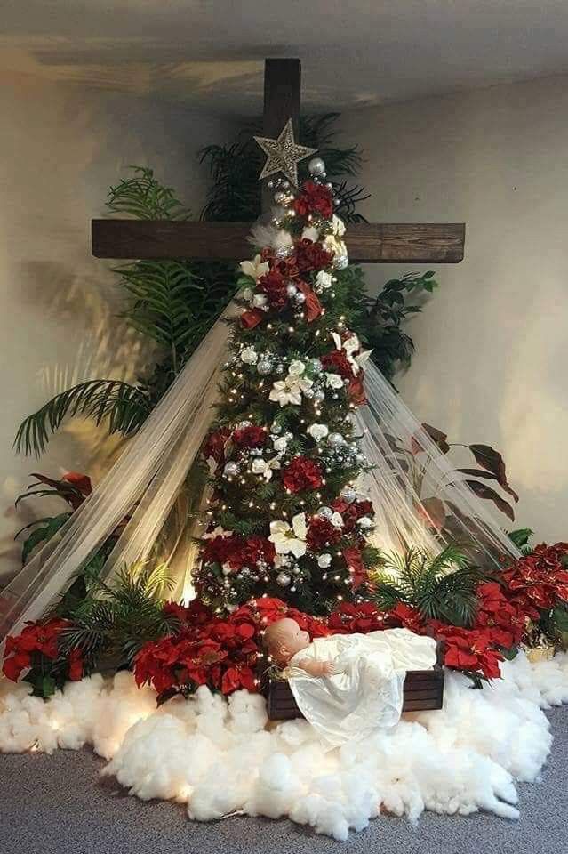 a christmas tree is decorated with red and white flowers, greenery, and a crucifix