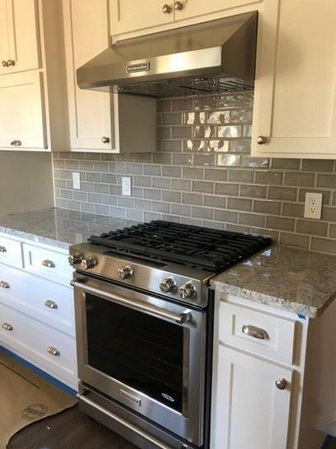 a stove top oven sitting inside of a kitchen next to white cupboards and drawers