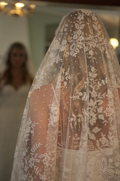 a woman wearing a wedding veil in front of a mirror