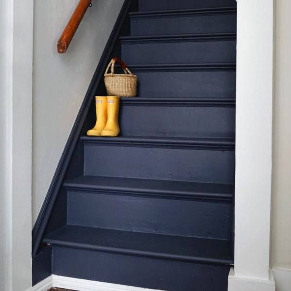 a blue staircase with yellow rubber boots and a basket on the handrail next to it