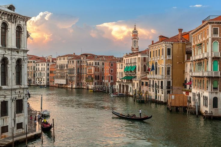 a boat traveling down a river next to tall buildings on either side of the water