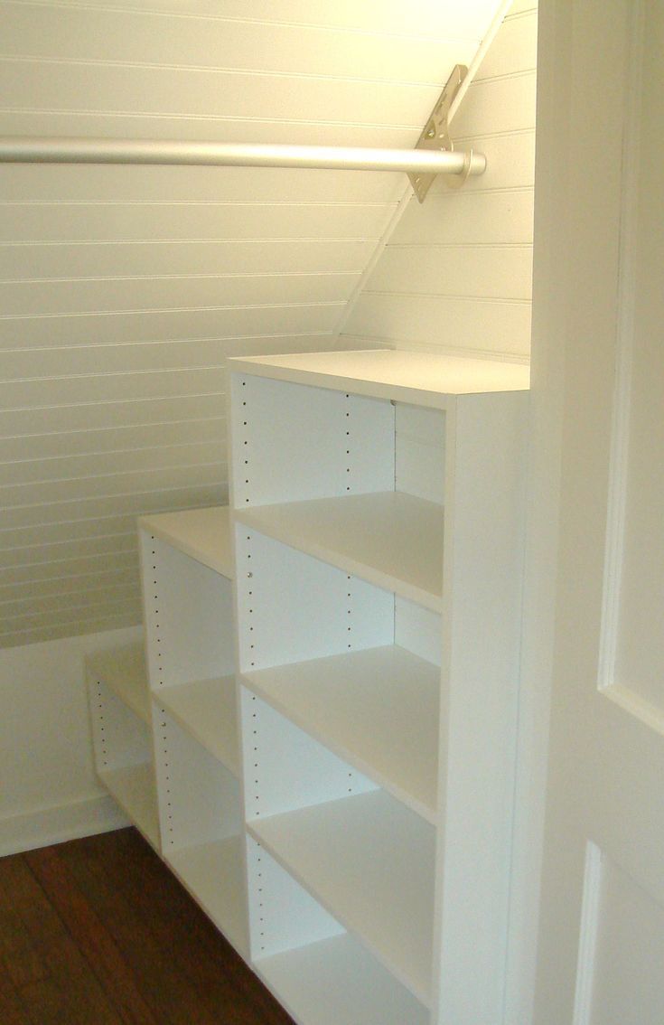 an empty room with white shelving in the corner and wood flooring on the other side