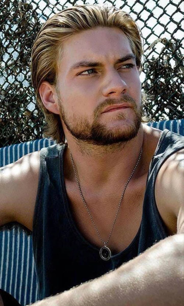 a man sitting in front of a chain link fence with his hand on his hip