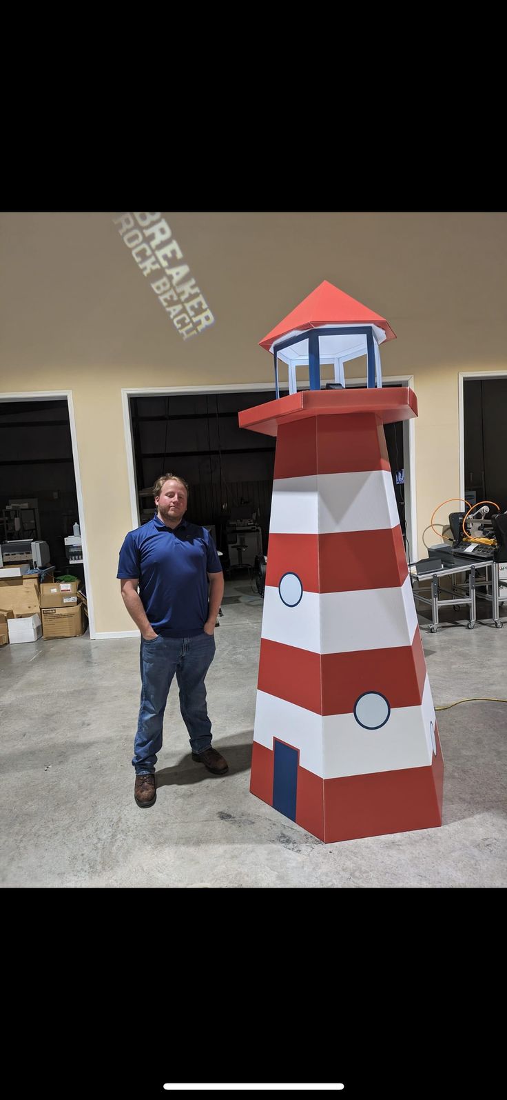 a man standing in front of a red and white lighthouse shaped like a house on wheels