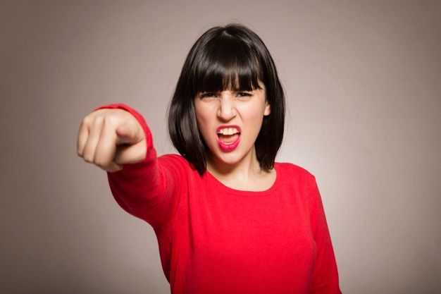 a woman in a red shirt is pointing her finger at the camera with an angry look on her face