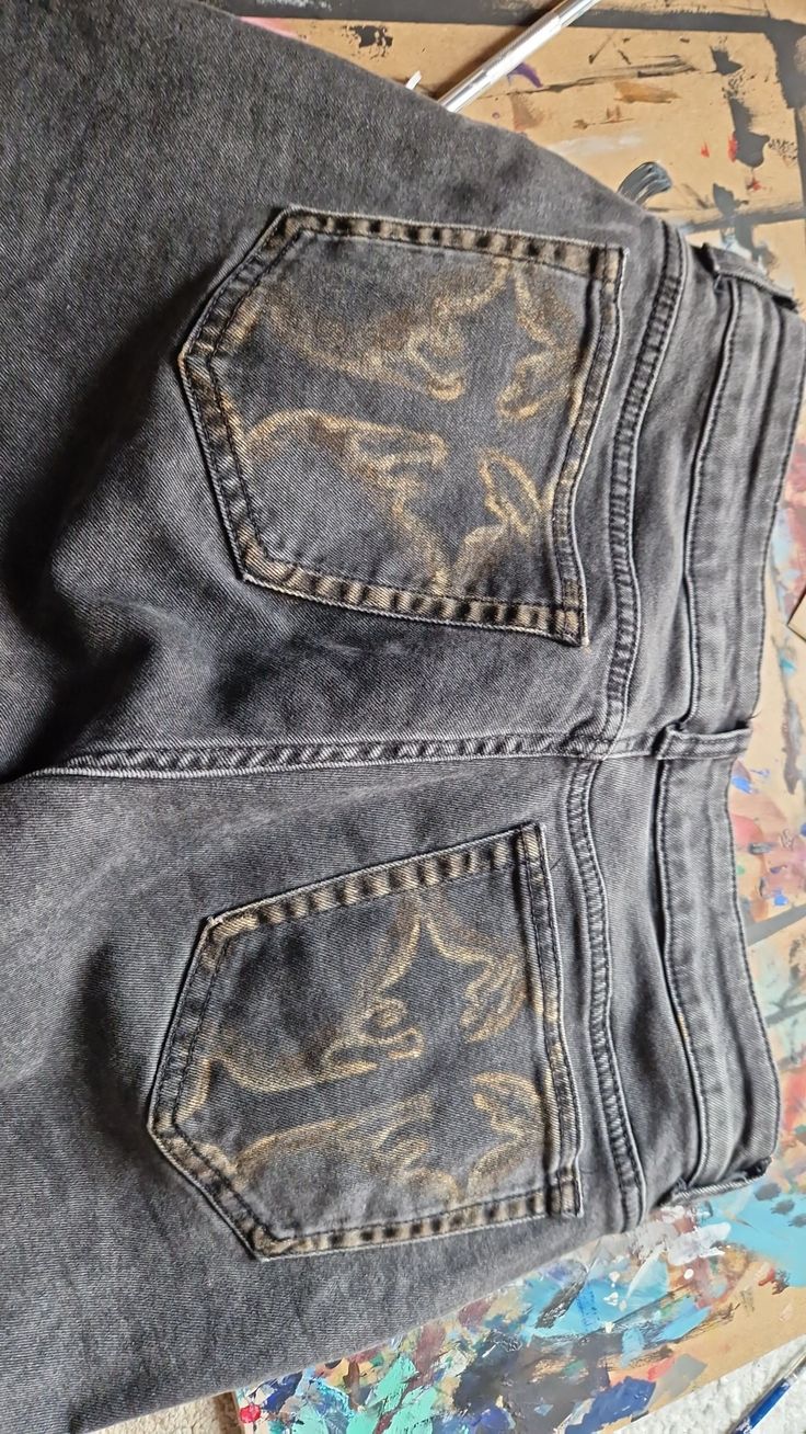 an old pair of jeans that have been painted with gold and silver paint on them