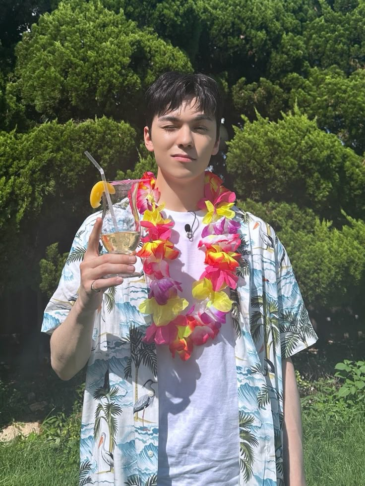 a young man wearing a lei and holding a drink