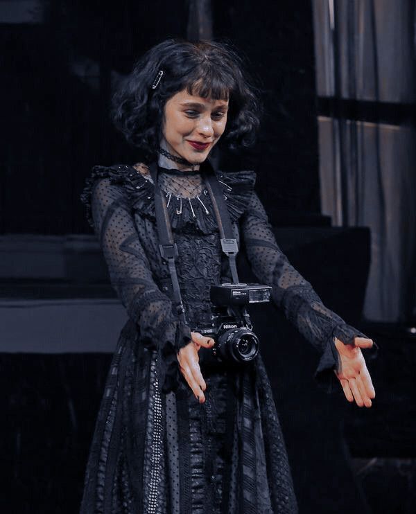 a woman dressed in black holding a camera