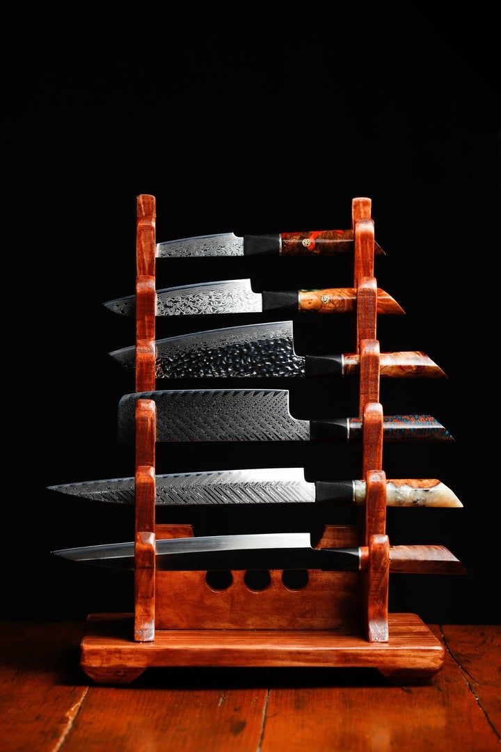 a knife holder with knives in it on top of a wooden table next to a black wall