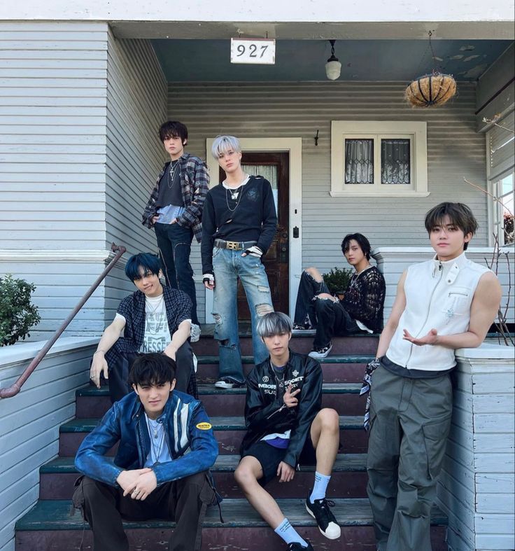 group of young men sitting on steps in front of a house with their arms around each other