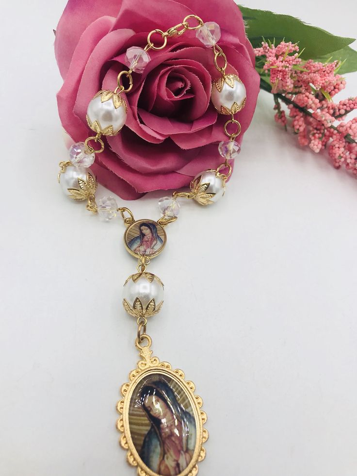 a necklace with a pink rose on it and an image of jesus in the center