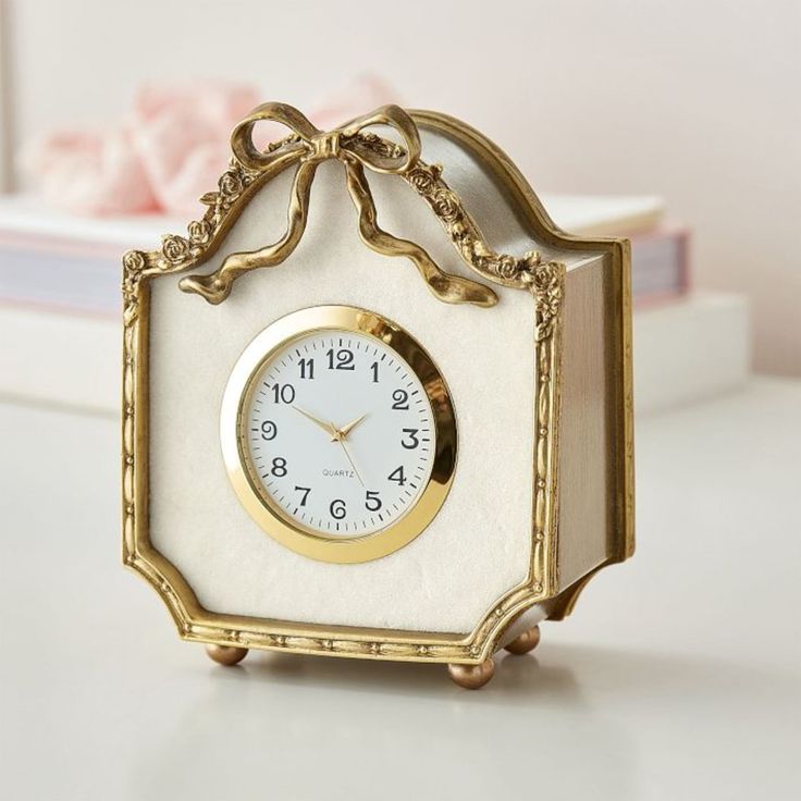 a white and gold clock sitting on top of a table