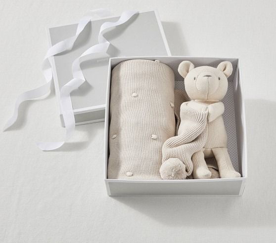 a white teddy bear and blanket in a box