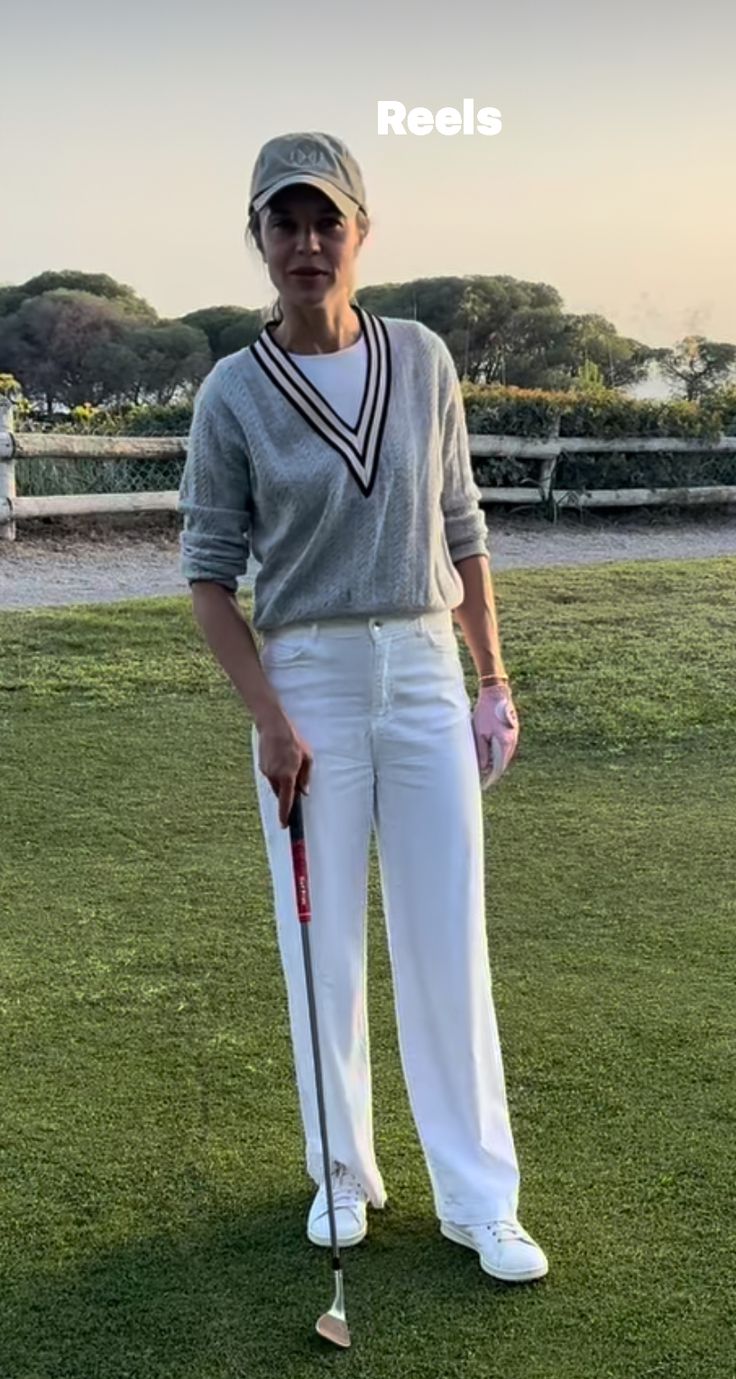 a woman standing on top of a lush green field holding a golf racquet