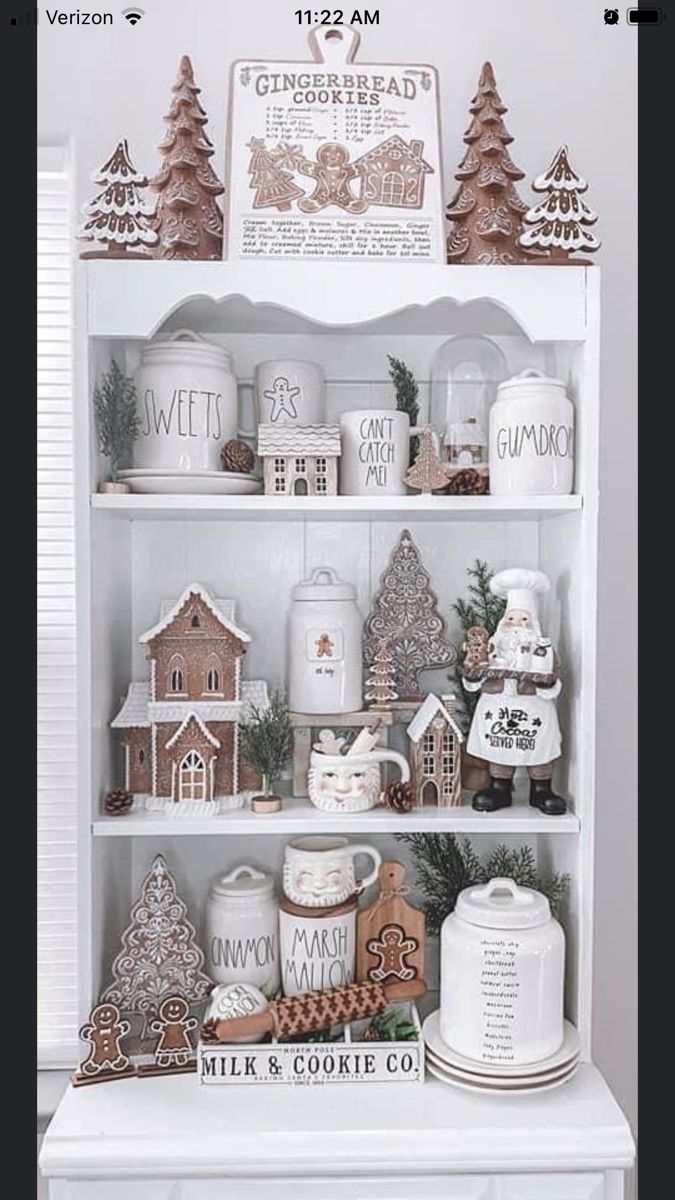 a white china cabinet with gingerbread houses and cookies on it's shelves for display