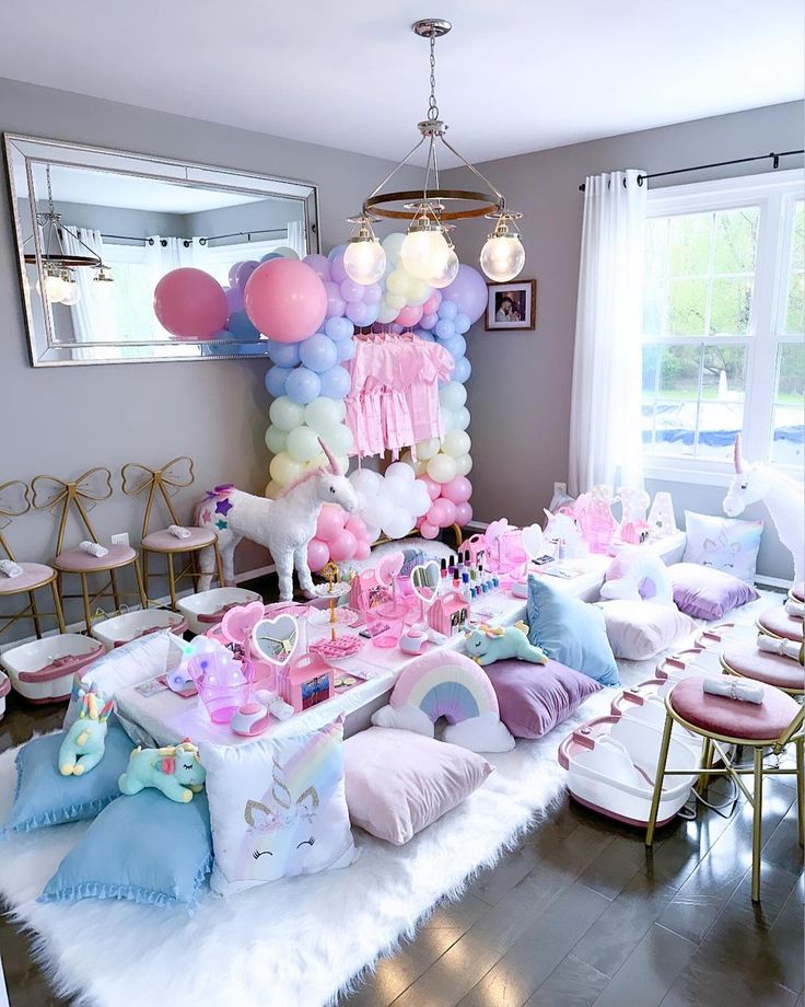 a room filled with lots of pink and blue balloons hanging from the ceiling next to chairs