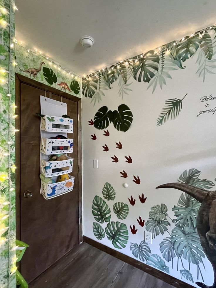 a dinosaur head is on the wall in a room with plants and leaves painted on it