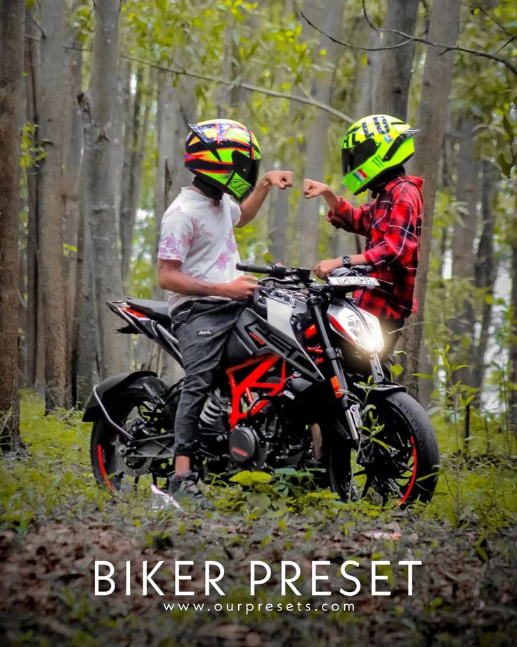 two people sitting on a dirt bike in the woods, one wearing a green helmet