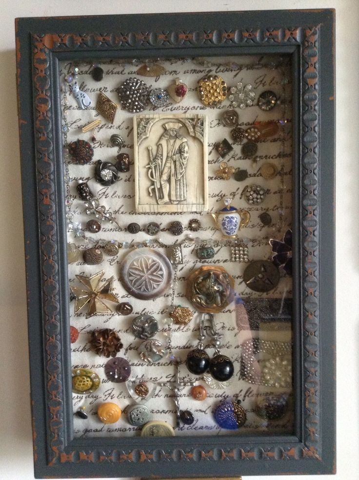 a shadow box is filled with buttons and other decorative items that are hanging on the wall