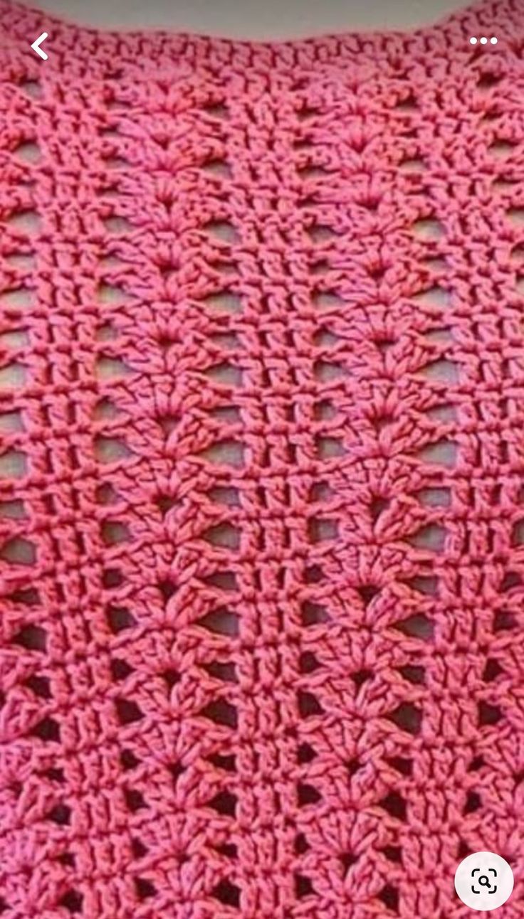 a pink crocheted blanket sitting on top of a table