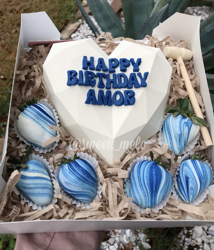 a birthday cake in a box with blue and white frosted chocolates on it