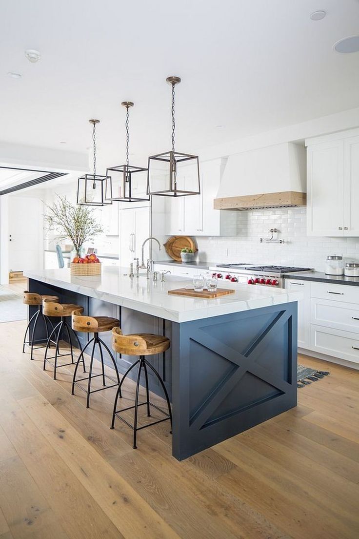 a kitchen with an island and bar stools in the center, surrounded by white cabinets