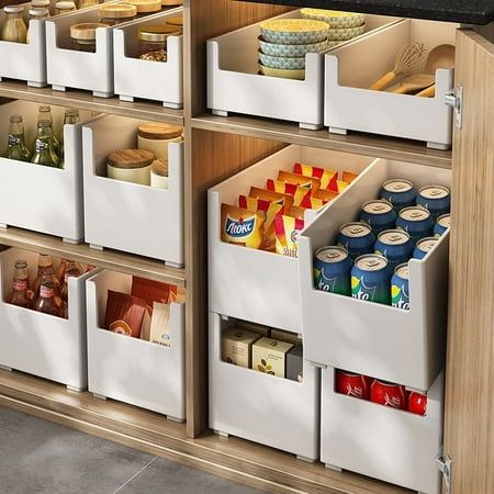 an organized kitchen cabinet filled with food and drink items, including canned foods in bins