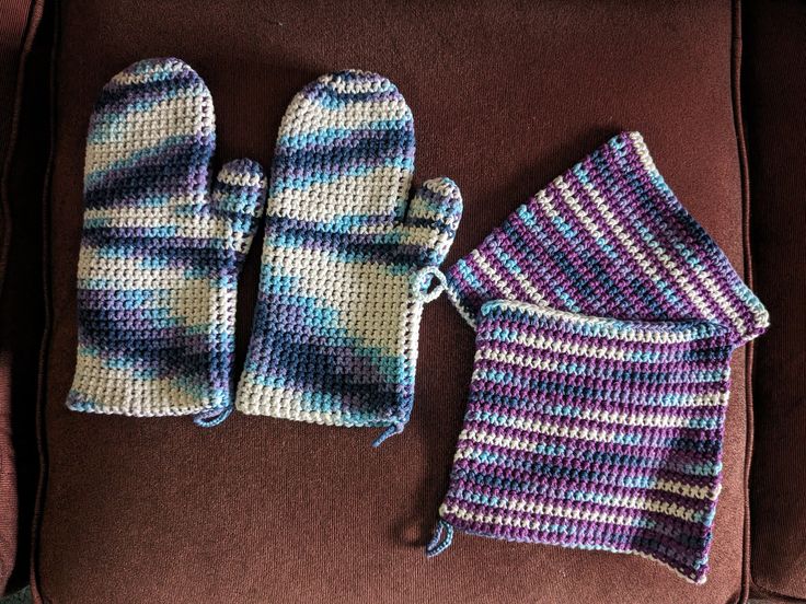 two knitted mittens and gloves sitting on top of a couch