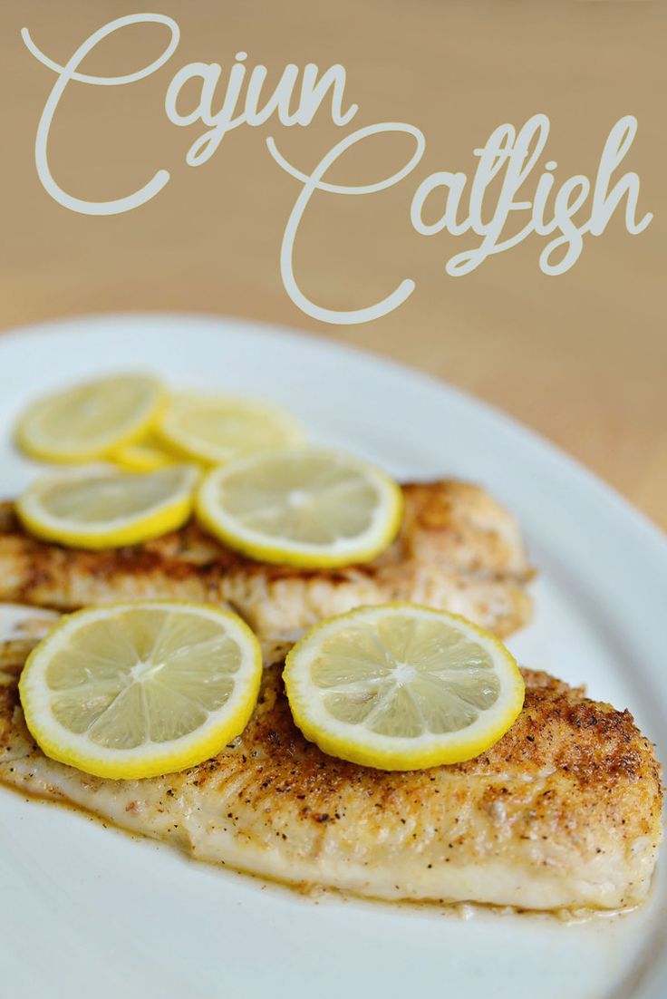 fish with lemon slices on a plate that says cajun catfish over it's image