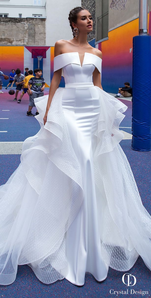 a woman in a white wedding dress standing on a basketball court with her hands behind her back