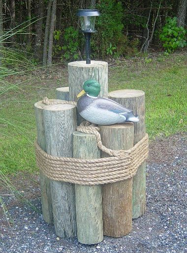 a duck sitting on top of a wooden post next to a lamppost with rope