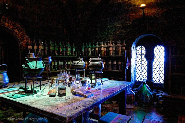 an old table with many bottles and beakers on it in a room filled with books