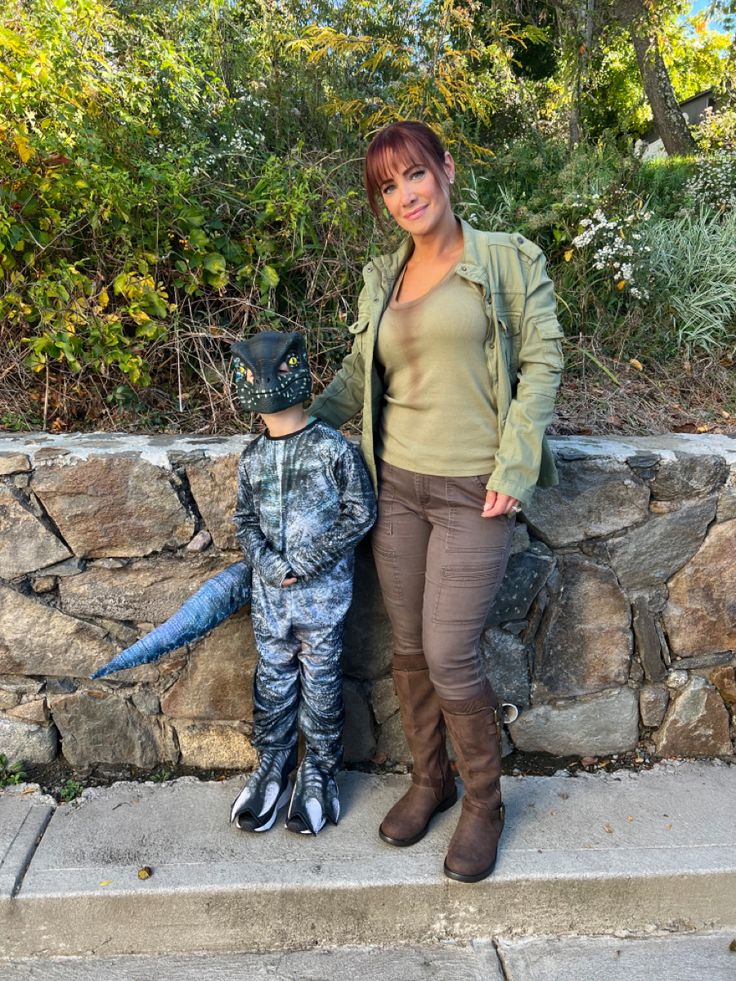 a woman standing next to a small boy in camouflage clothing with a helmet on his head