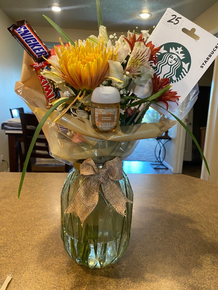 a vase filled with flowers on top of a counter next to a starbucks card holder