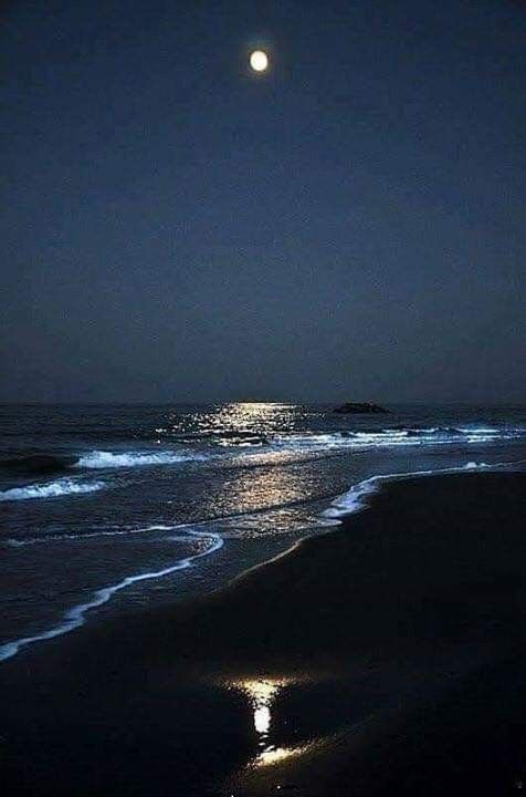 the moon shines brightly in the night sky over the ocean and beach as waves wash on the shore