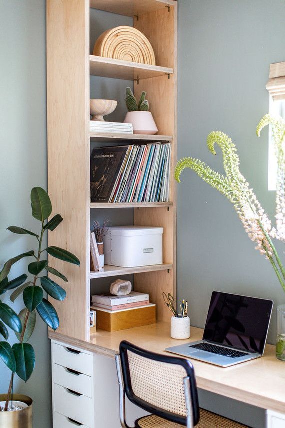 a laptop computer sitting on top of a wooden desk next to a book shelf filled with books