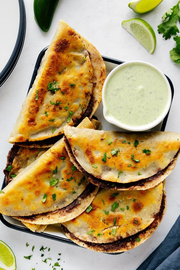 several quesadillas on a plate with a small bowl of ranch dressing next to them