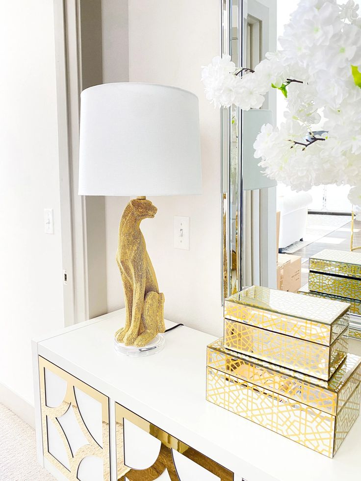 a lamp sitting on top of a white table next to a mirror and some boxes