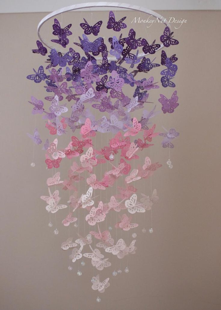 some pink and purple butterflies are hanging from a chandelier in a bedroom or playroom