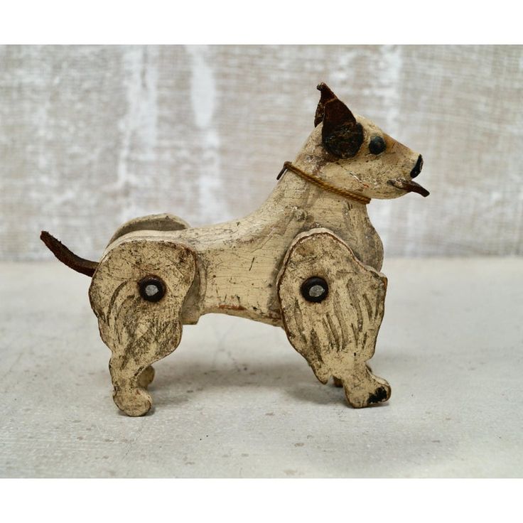 a small wooden dog figurine on a white surface with a brown collar and black eyes