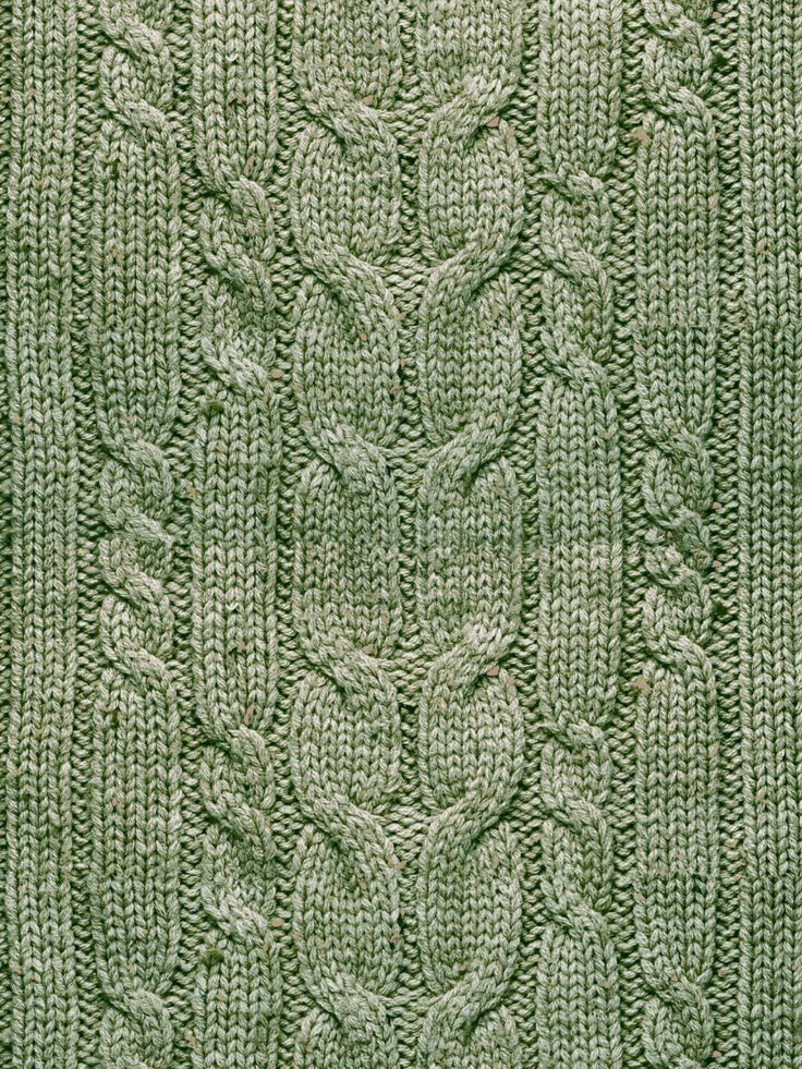 a green knitted blanket with leaves and vines on the front, in shades of light green