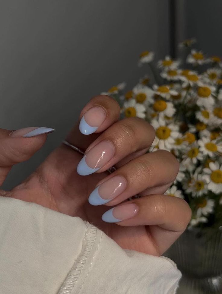 A hand with medium long nude nails painted with light blue French tips #womensfashion #naildesign #springnails #nails #naildesigntrends Spring Nails 2024 Trends French, Simple Almond Acrylic Nails, Blue Tip Nails, Pastel Blue Nails, Ladybug Nails, Blue Prom Nails, Grad Nails, Nail Ideas Simple, Almond Acrylic