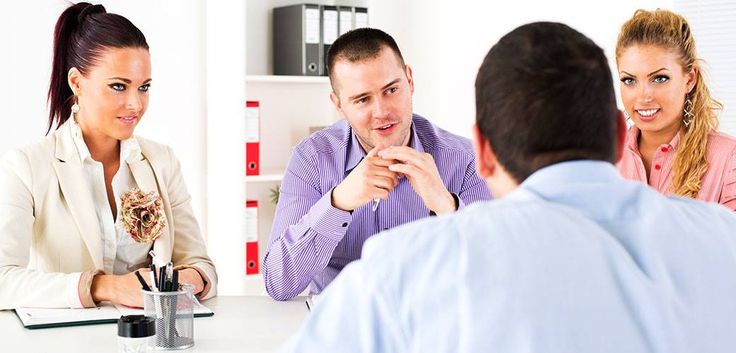 three people sitting at a table talking to each other in front of a man and woman