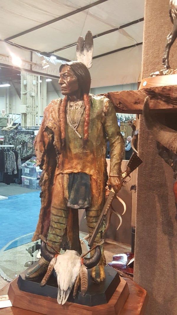 a statue of a native american standing next to a cow skull on display in a store