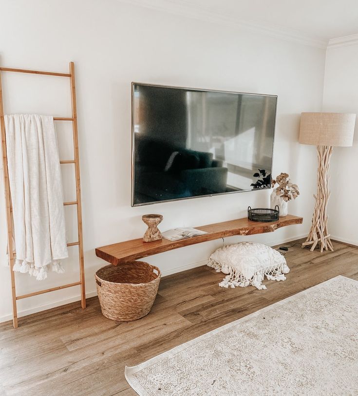 a living room with white walls and wood flooring has a large tv mounted on the wall