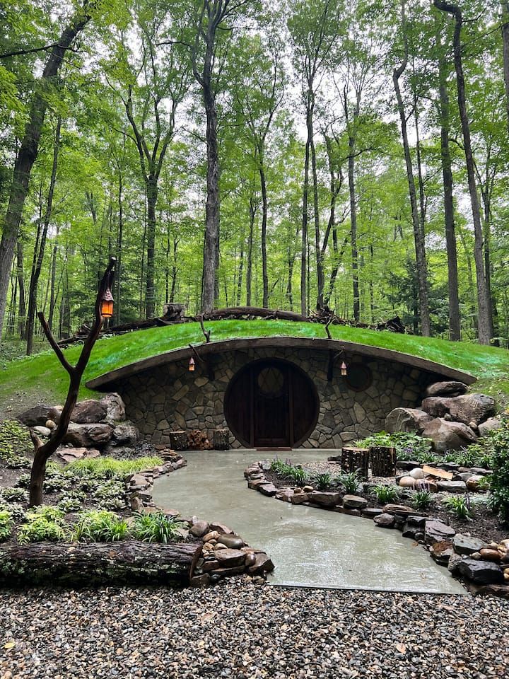 a stone bridge in the middle of a forest with lots of green grass on top