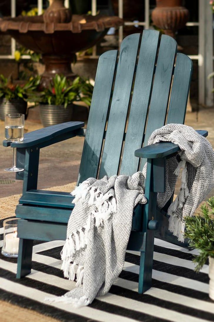 a blue wooden chair sitting on top of a black and white striped rug next to a potted plant