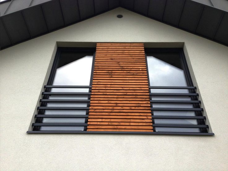 a window with wooden slats on the side of a white wall and black trim